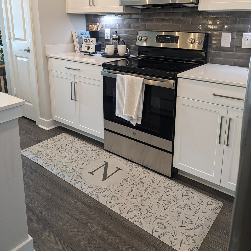 Botanical runner mat monogrammed with N in the middle of the mat that's placed in a kitchen in front of the stove.