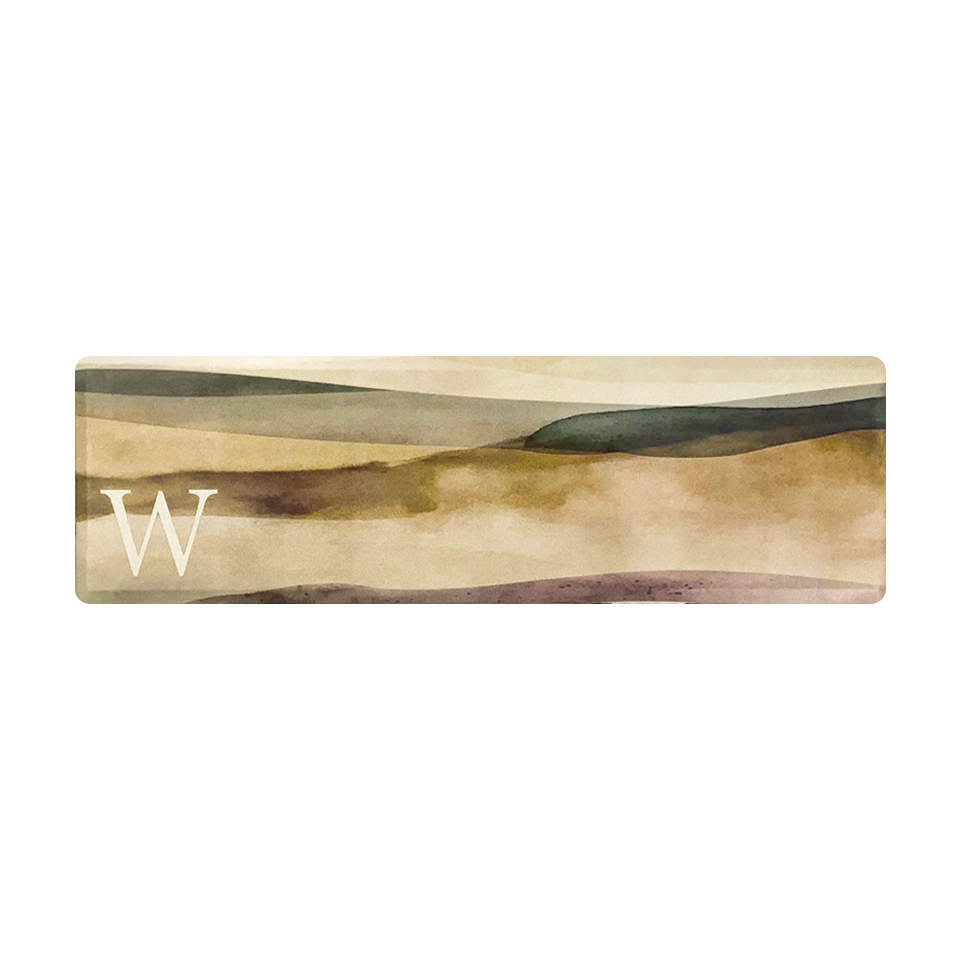 Overhead image of high quality anti-fatigue mat with a watercolor abstract landscape design and a monogrammed letter in white.