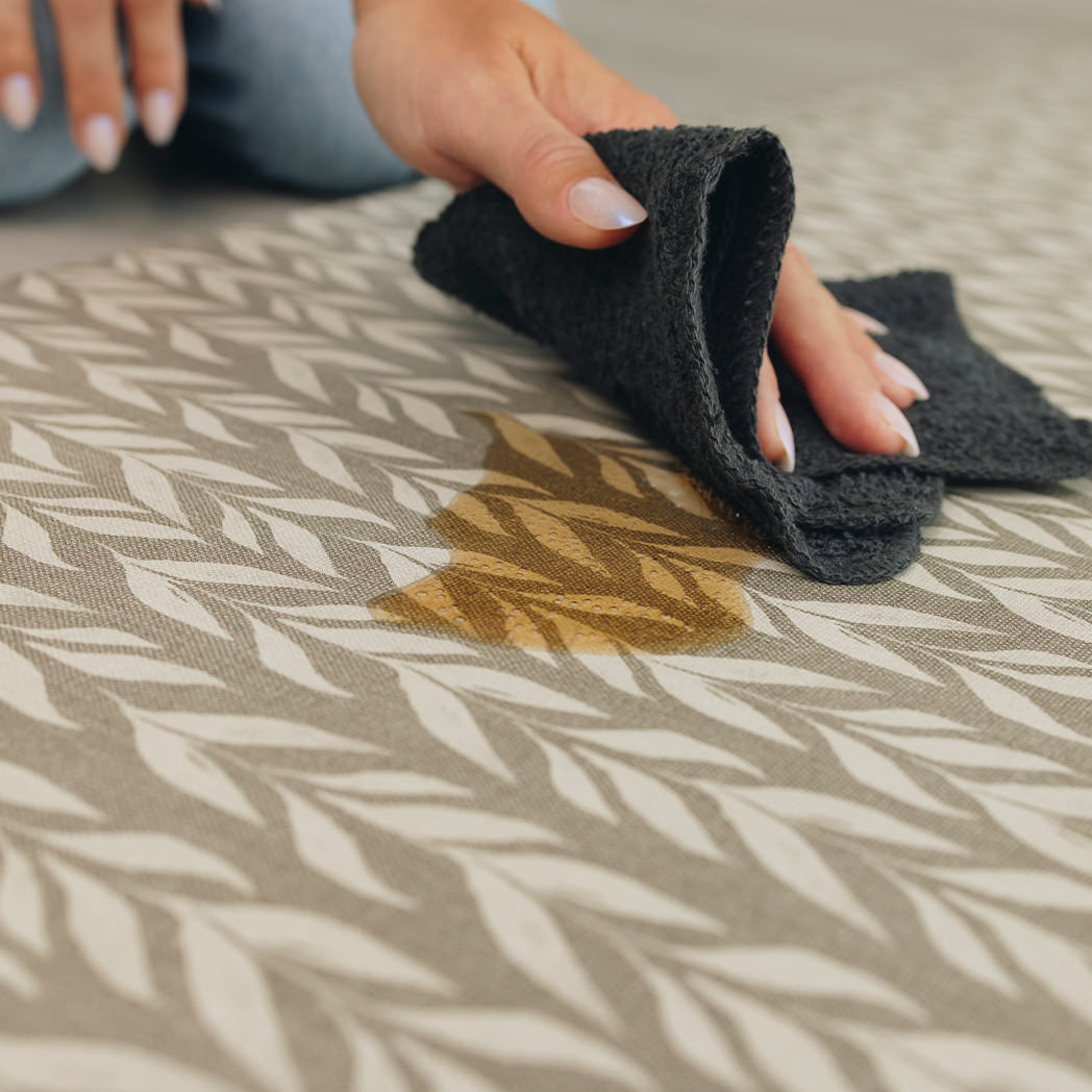 Woman easily wiping up a spill of soda on a waterproof Happy Feet comfort mat