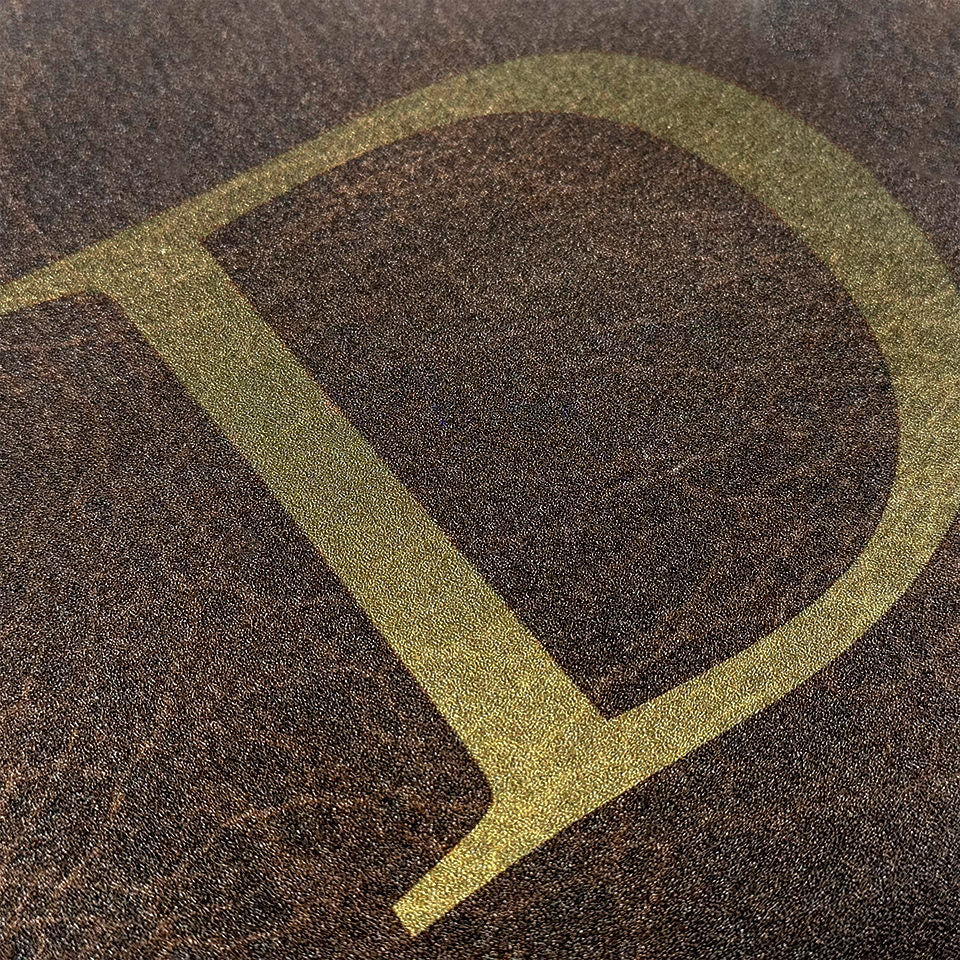 Detailed image of Leather's monogrammed letter featuring an ombre gold serif font.