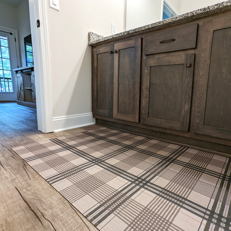 Low-profile and rubber backed Un-Rug shown in brown and tan plaid pattern is placed in front of double bathroom vanity.