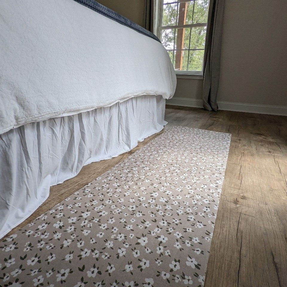 Low-Profile Un-Rug Decorative runner accent mat in the floral Tiny Flowers design in Grey is placed next to a freshly made bed and being used as a bedside runner rug.