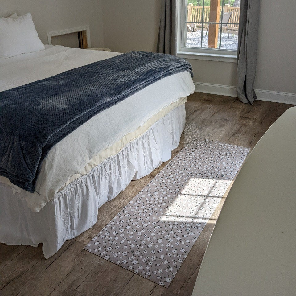 Low-profile and machine washable Un-Rug Tiny Flowers decorative accent mat placed at the foot of a queen size bed.