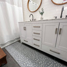 Sea salt blue linen background with tiny white and green flowers on an indoor washable rubber-backed bathroom runner mat placed in front of a double vanity.