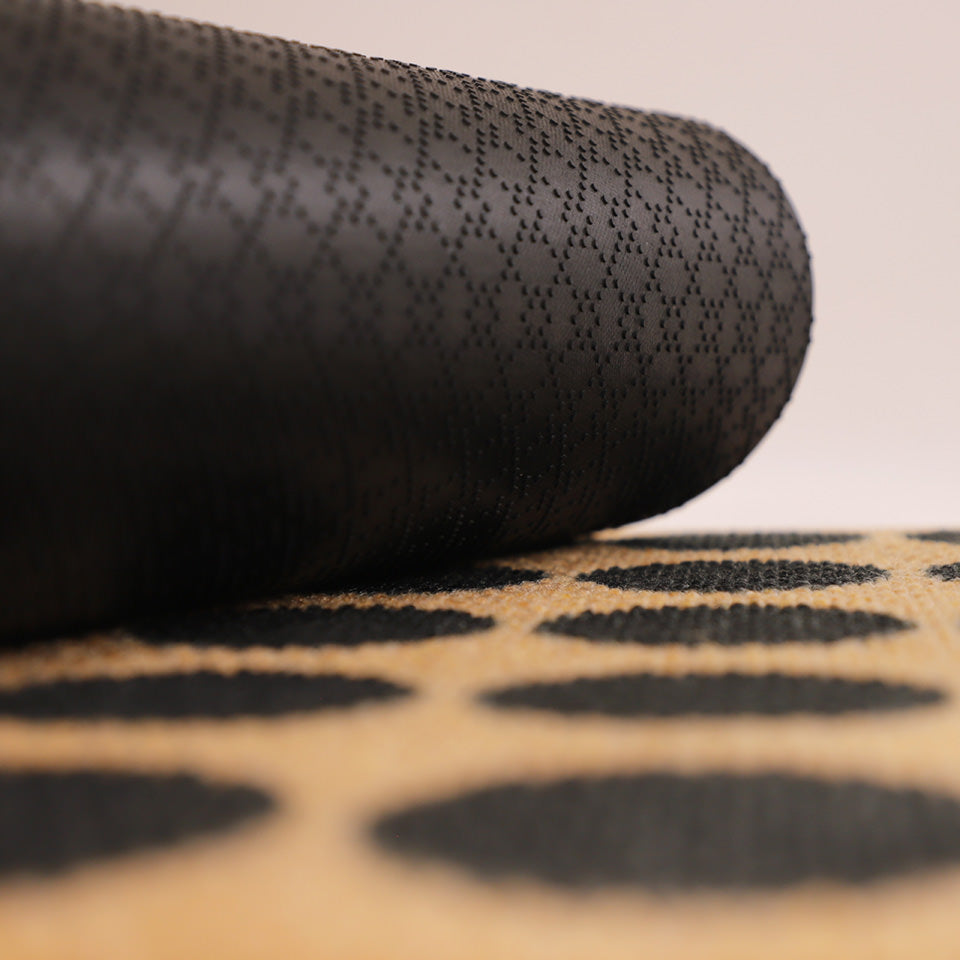 Image of rubber backing rolled up on a black, white, and coir Lucky Numbers mat.