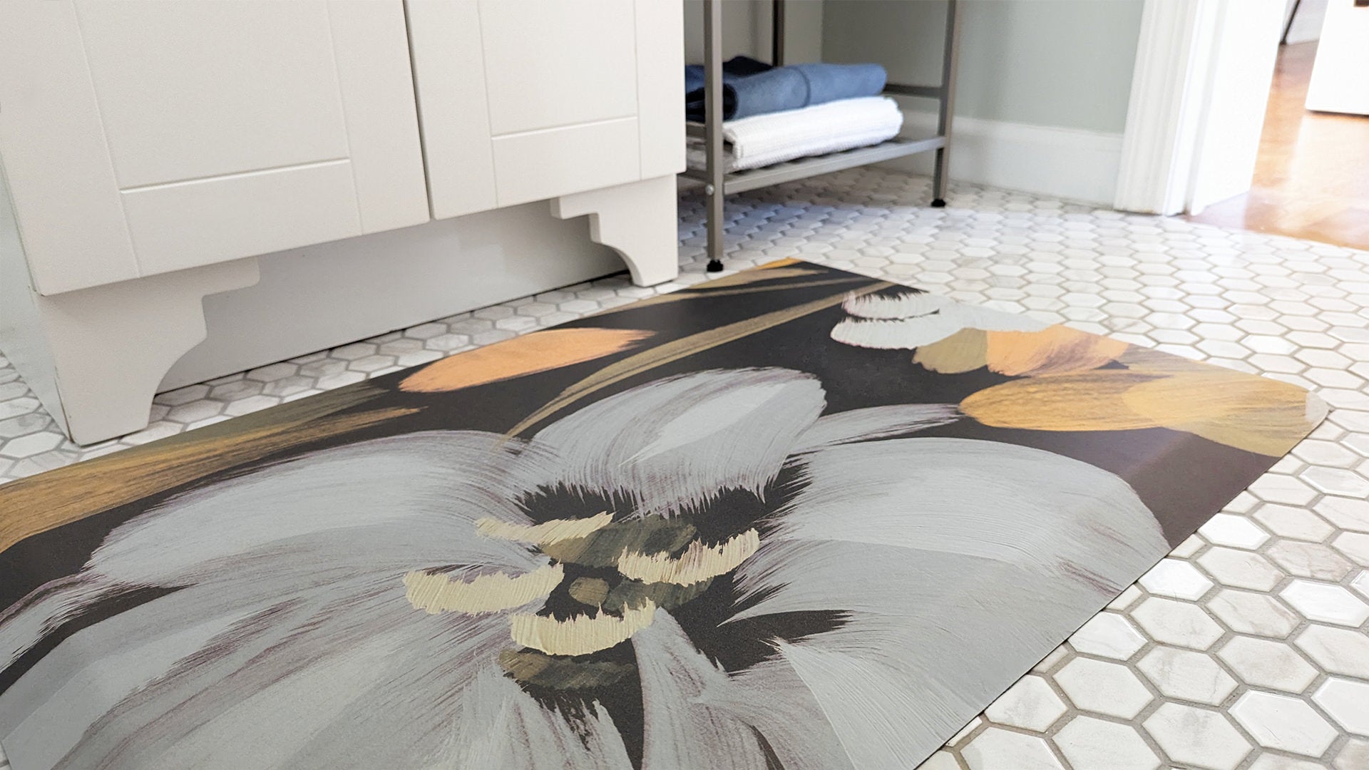 Happy Feet Comfort Mat used as a bathroom mat and placed in front of a single sink vanity on white tile floor.