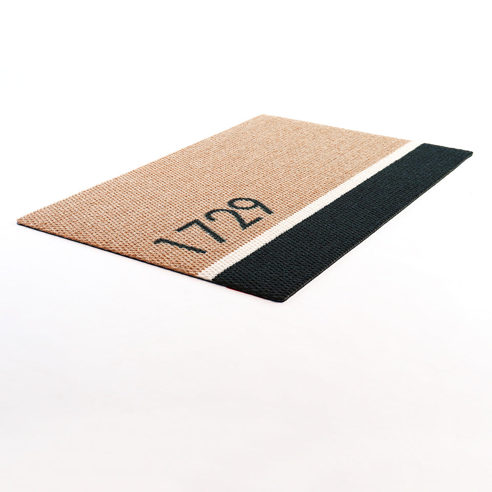 Angled shot of Modern Main personalized doormat featuring house number on tan/black/white classic design