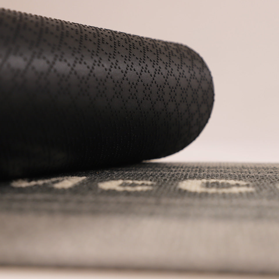 Image of the rubber backing rolled up on Modern Moniker’s non-shed personalized grey surface.
