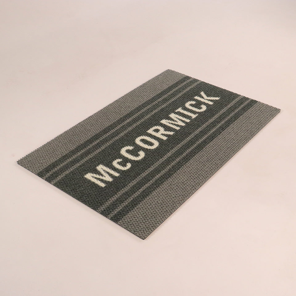 Angled single door Modern Moniker mat personalized with last name on a grey mat with grey stripes.