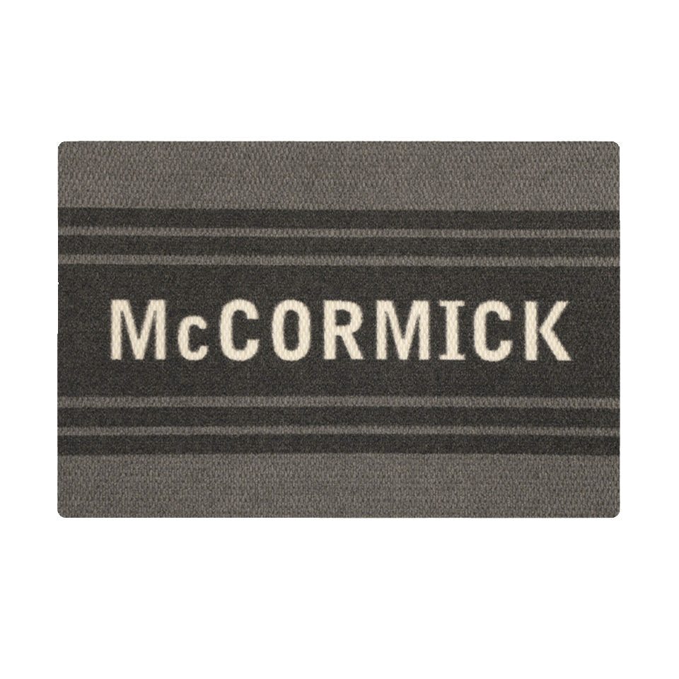 Overhead of single door Modern Moniker mat, personalized name on dark grey bar with two  lines on a grey background.