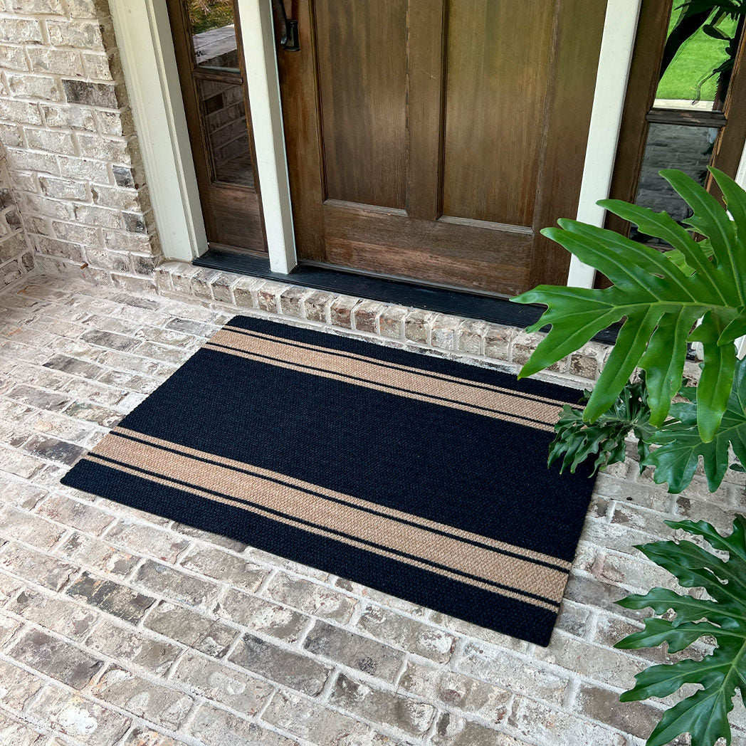 Black doormat with coir stripes that's a little bigger than a single door; doesn't shed