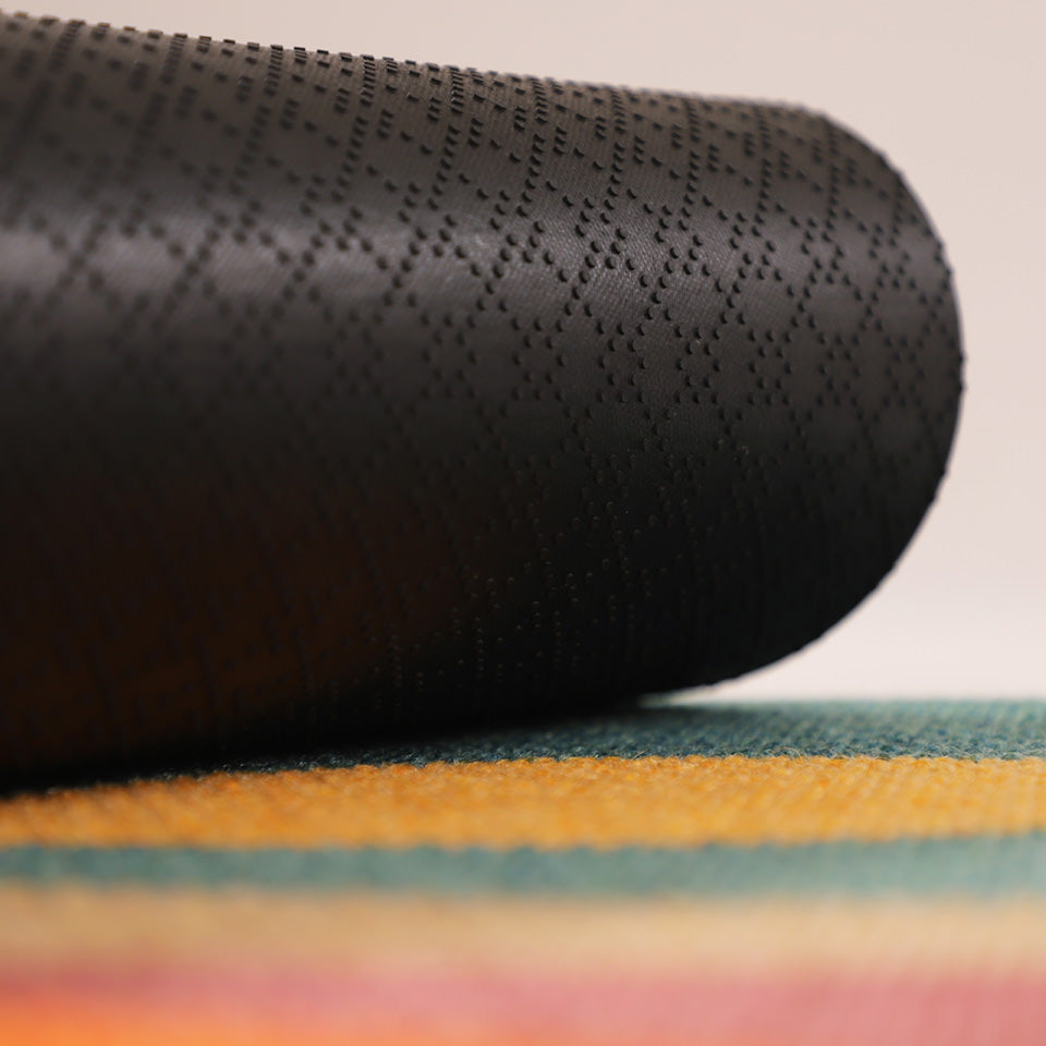 Image of rubber backing rolled up on the vibrant Personal Sunset non shed mat.