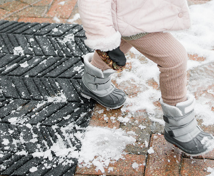 WaterHog Luxe outdoor doormat in dark grey graphite color scrapes and contains snow from young child's boots.