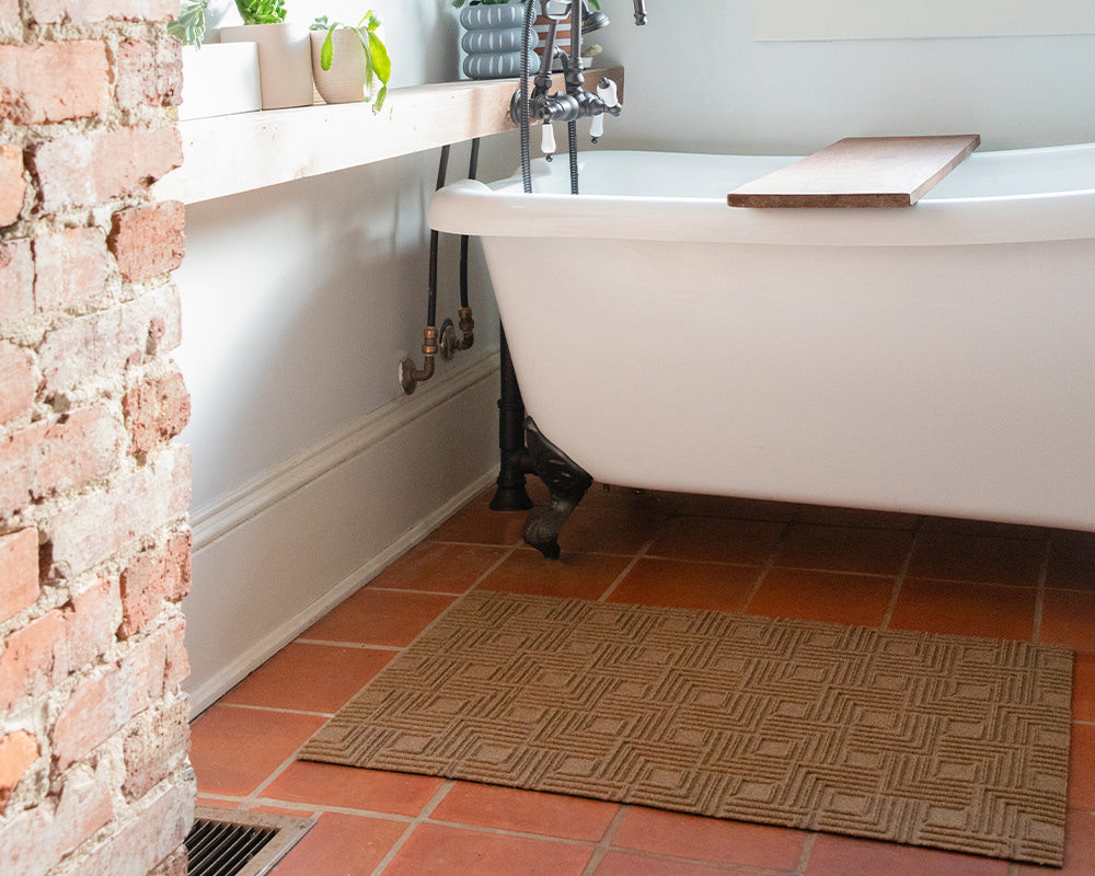 Incredible WaterHog Luxe low-profile mat in the geometrical Labyrinth design in wheat, protection tile floors next to a bathtub.