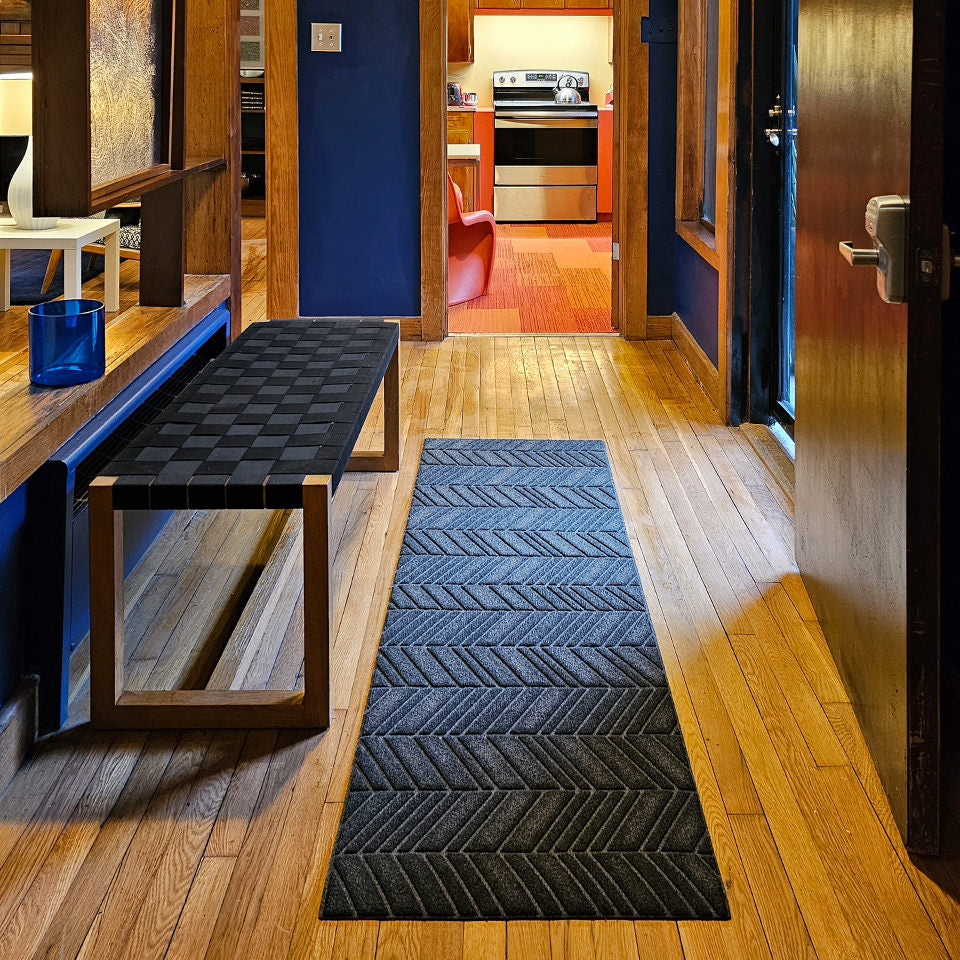 Double door WaterHog Luxe In Vein in charcoal down a hallway entrance accenting the dark wall paint and furniture on a light oak wood floor.