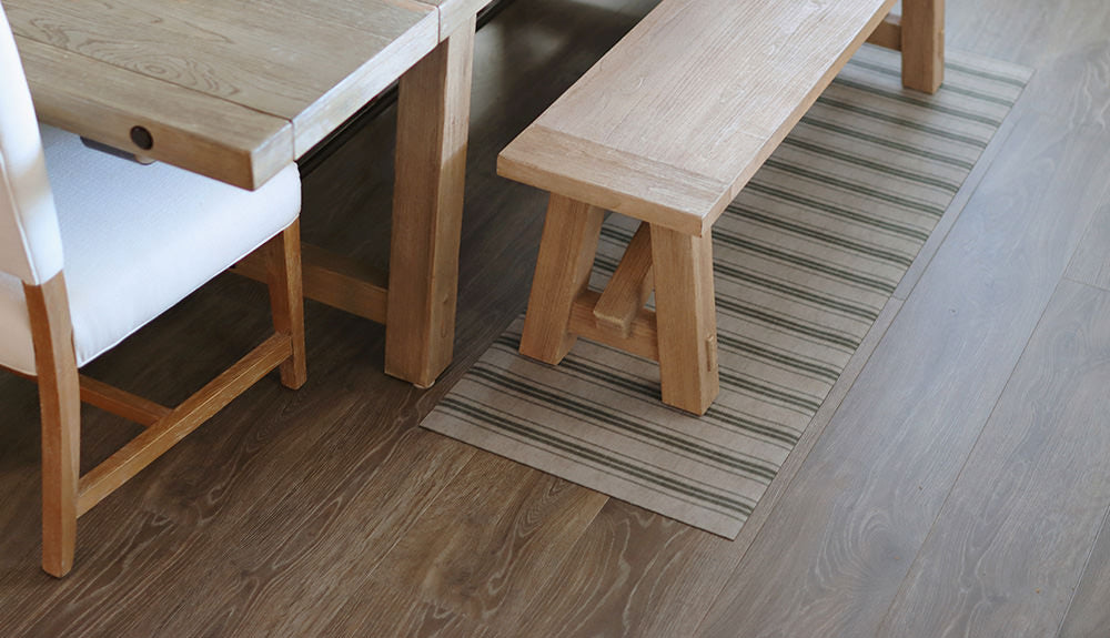 A low profile Un-Run mat located under a natural wood table bench.