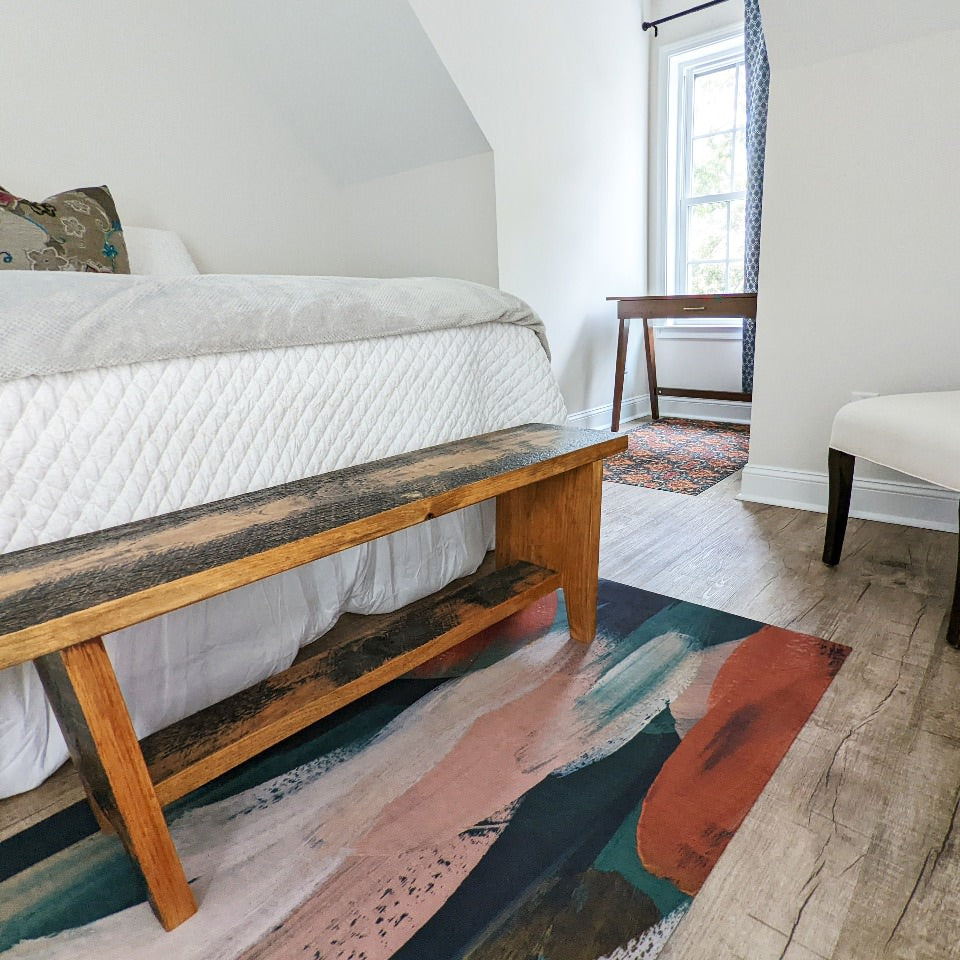 Low-profile rubber backed accent rug placed at the foot of a bed prevents scratches from a wooden bench placed on top.