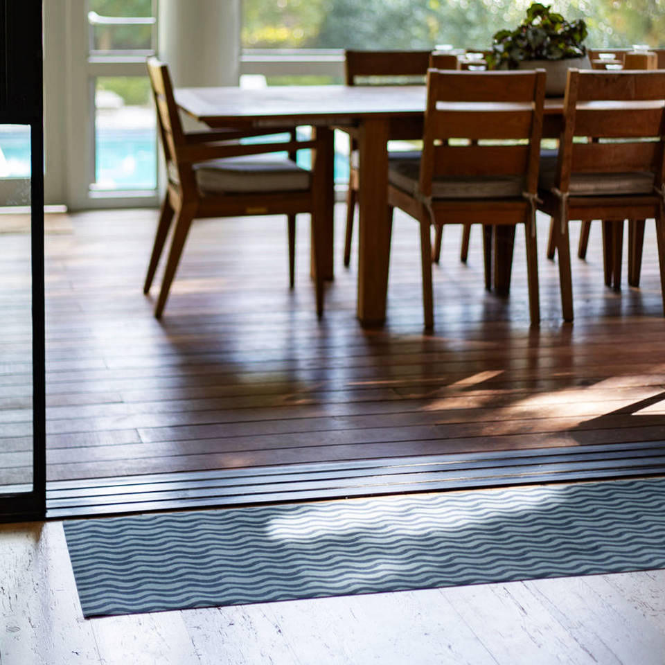 Un-Rug in Coastal Stripe design with durable rubber backing protecting entryway to a covered deck.