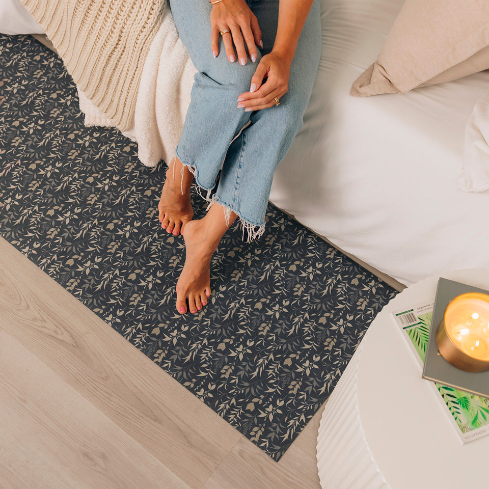 Overhead over a Ditsy Floral Un-Rug runner mat at the side of a bed with a woman sitting on the edge of the bed.