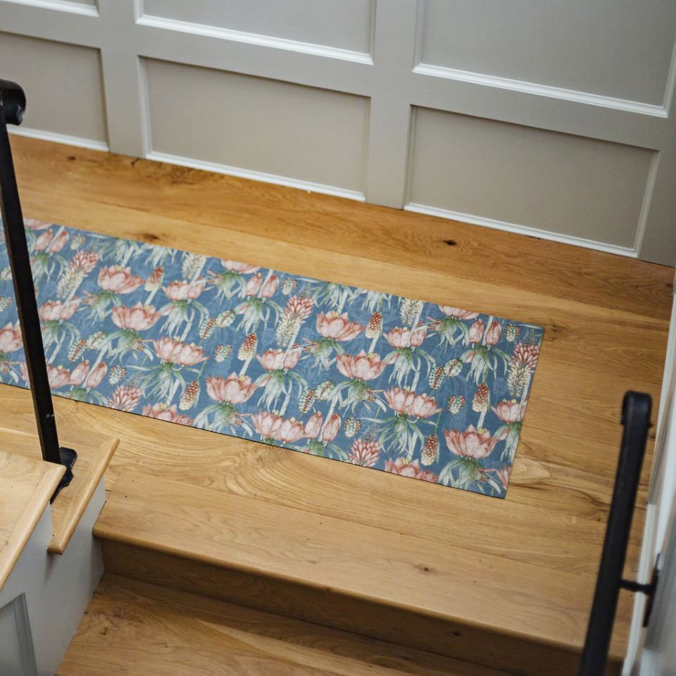 Overhead shot of Dark floral print with pink flowers on blue grey background on a low profile washable floor mat