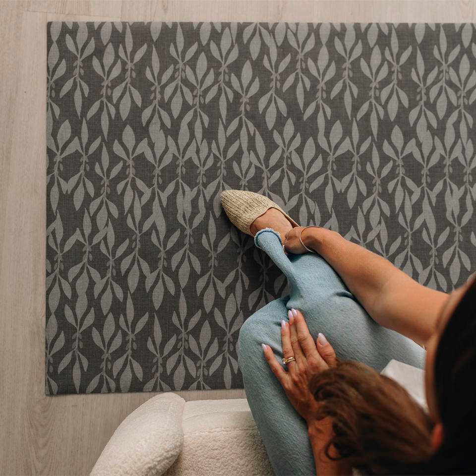 Overhead image of Un-Rug's Leaf Motif mat with a girl on a couch with her legs stretched out.