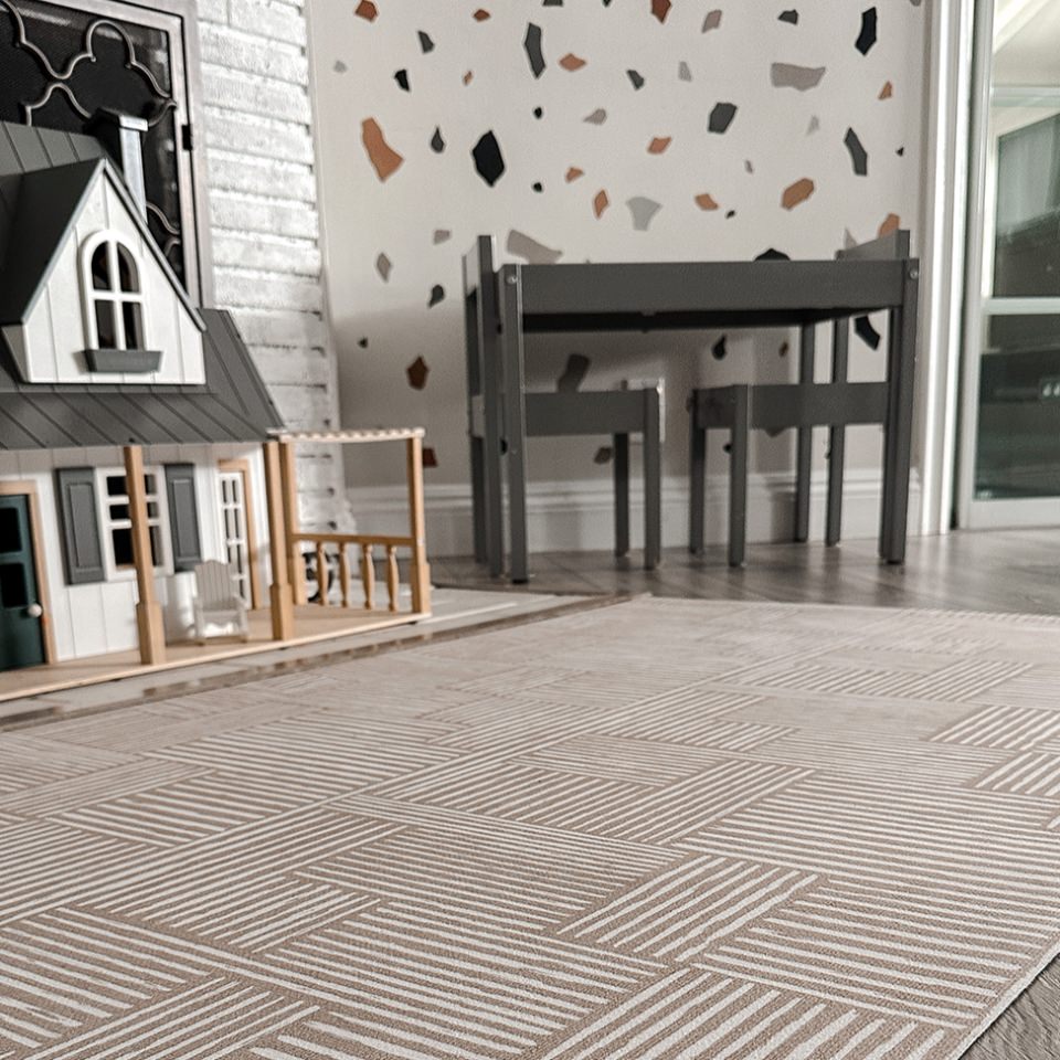 Modern low-profile and machine washable accent rug is used as a playmat placed in front of a dollhouse.