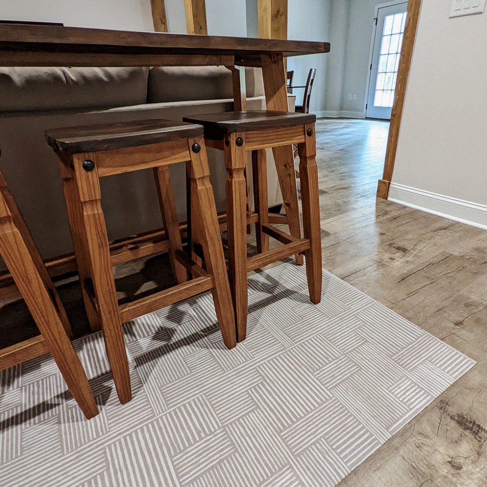 Low-profile Un-Rug accent mat in Organic Lines design placed at the base of a counter and protects floors from scratches due to barstools.