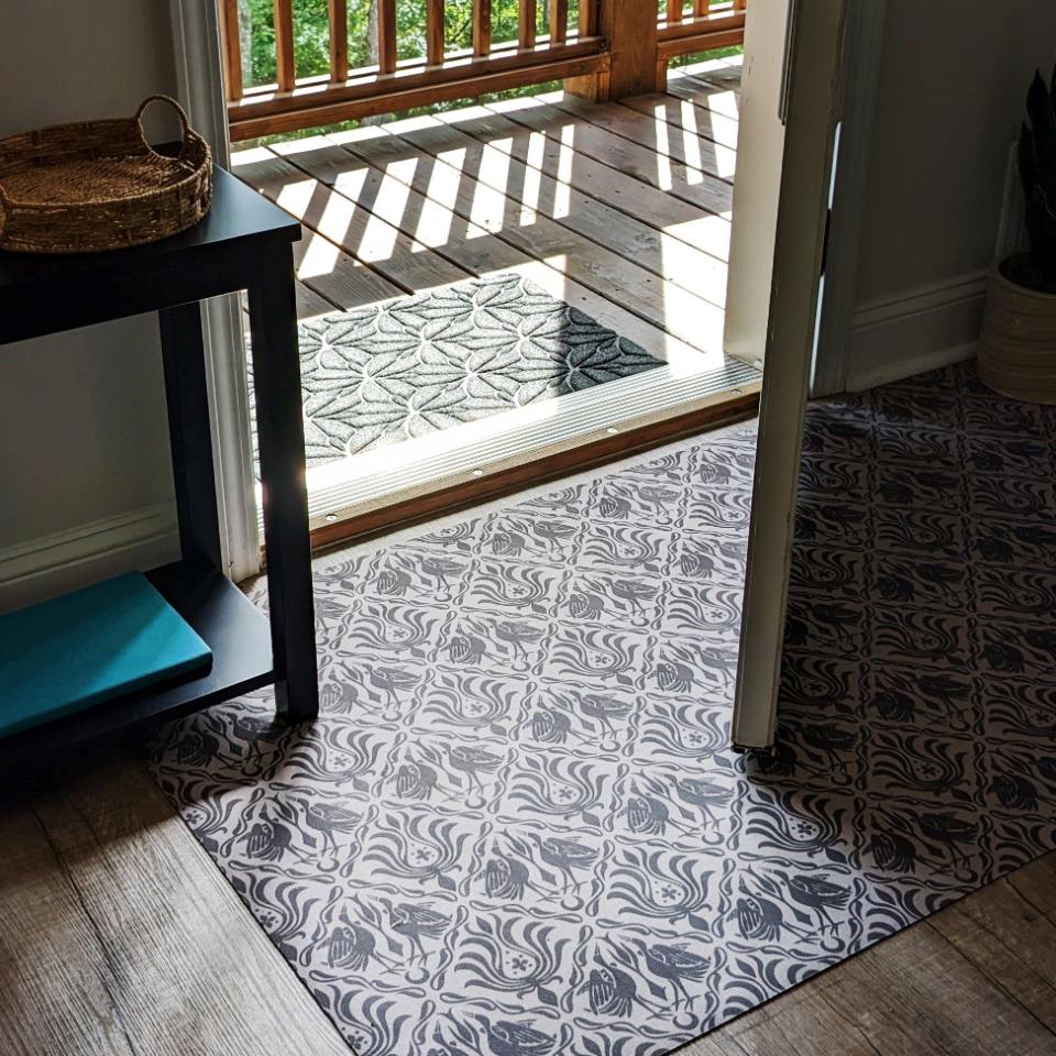 Un-Rug low-profile accent rug in Urbane bronze ornamental cranes design placed just inside a front door.