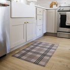 Low-profile and rubber backed Un-Rug shown in brown and tan plaid pattern is placed in front of a kitchen sing.