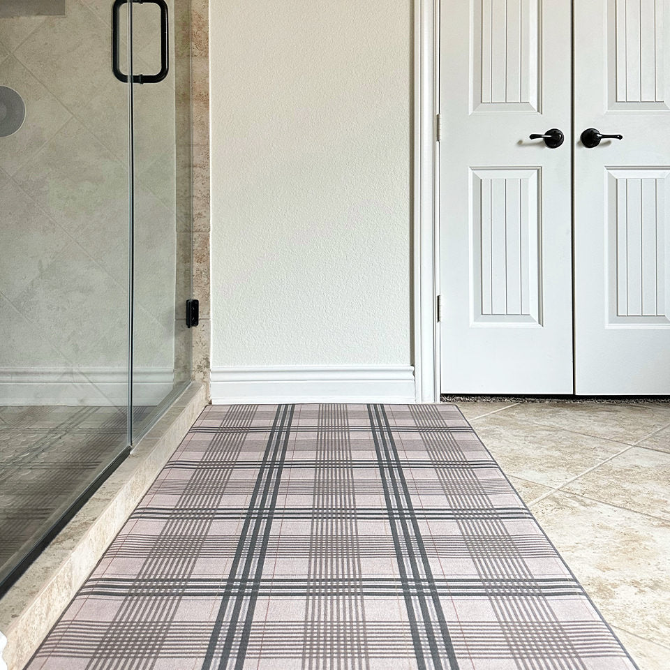 Low-profile and rubber backed Un-Rug shown in brown and tan plaid pattern placed outside a shower for better traction.