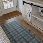 Un-Rug sea salt blue Oxford plaid low-profile mat in front of a couch in the livingroom.