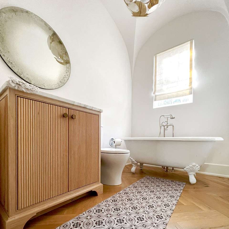 Un-Rug low-profile accent mat in the Piezza design featuring a neutral palette is used to protect bathroom floors.