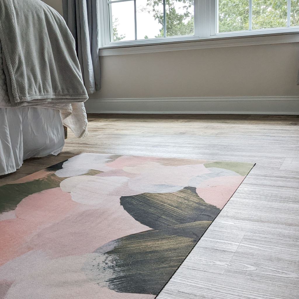 Ultra low-profile Un-Rug decorative mat in the Abstract Painting design placed next to a bed.