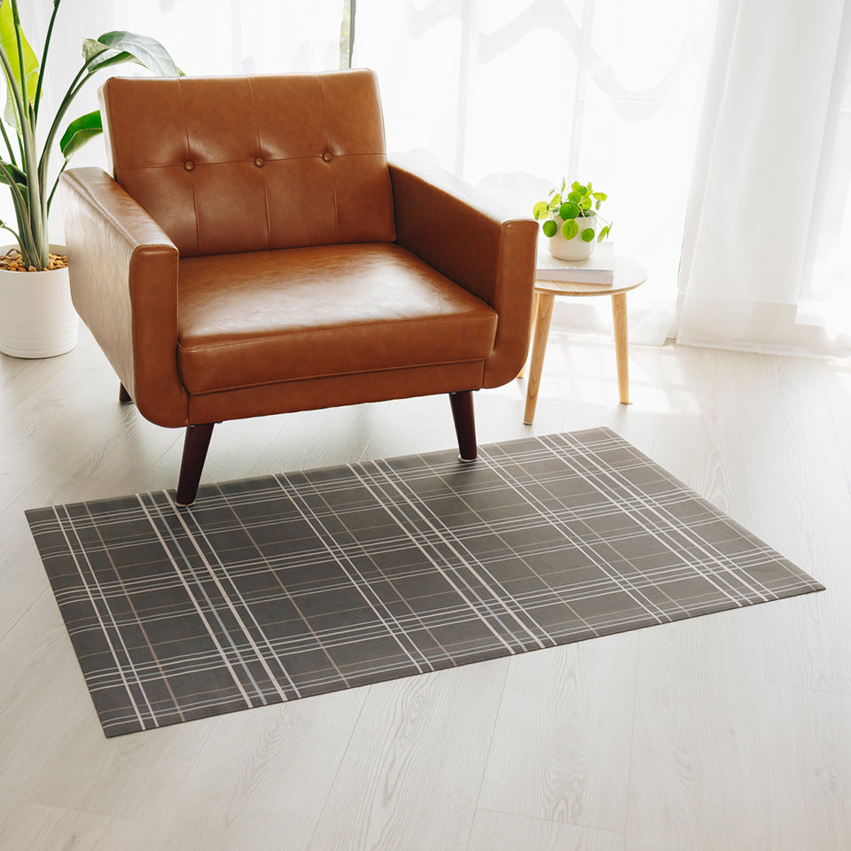 Sydney Plaid Un-Rug in a living room in front of a chair for floor protection.