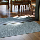 Low-profile and rubber backed Un-Rug placed in the entrance of a home off a deck in a delicate floral design.