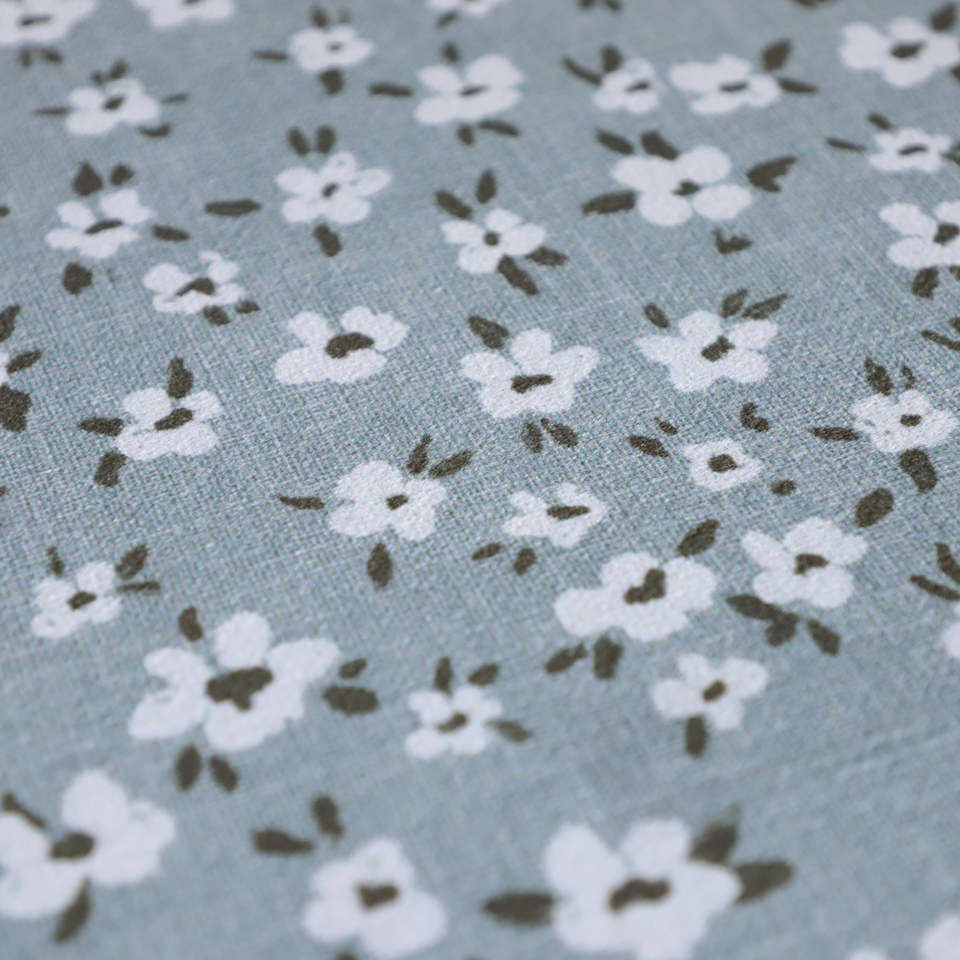 close up of soft knitted fabric in sea salt (light blue) covered in small white flowers