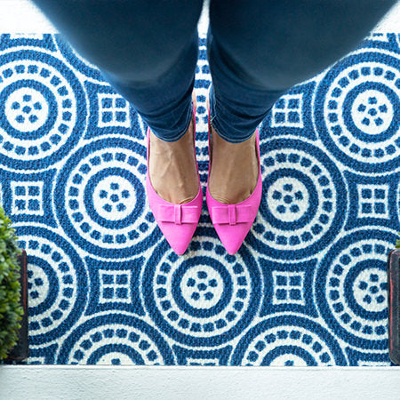 Pink shoes on top of low profile blue and white circle medallion doormat 