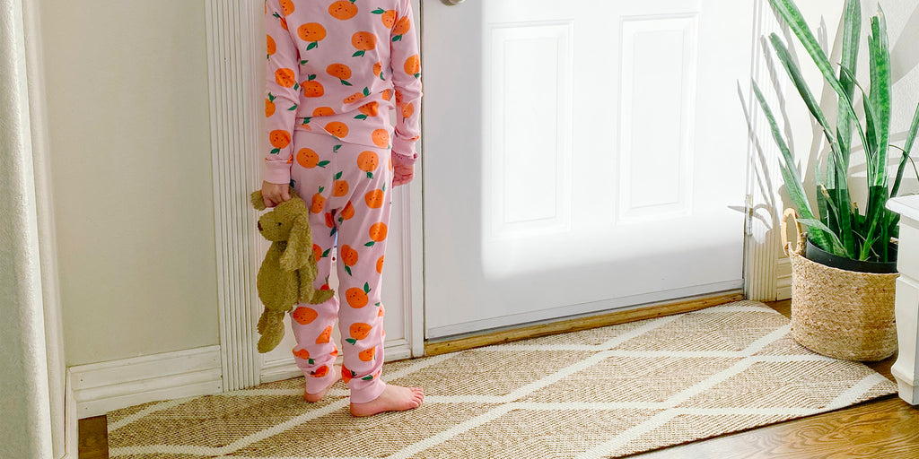 Child standing at front door on low profile non shedding doormat in coir and white