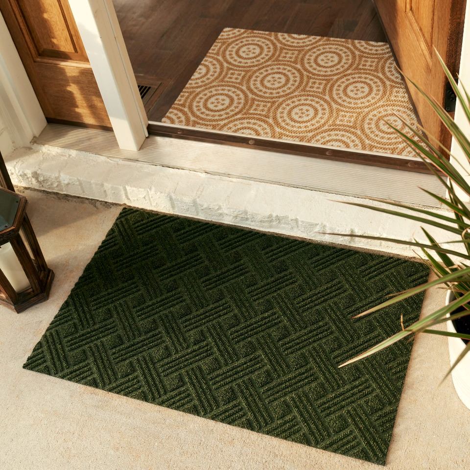 Single door sized WaterHog Luxe classic thatch doormat in olive placed outside front entryway paired with coir and white medallions mat inside entryway.