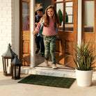 WaterHog Luxe classic thatch single sized doormat placed outside entryway with children walking through door.