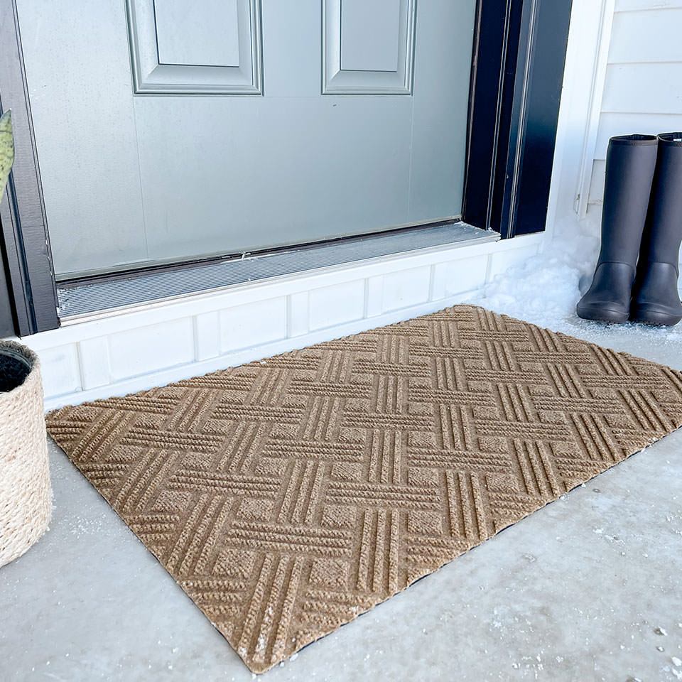 Single door WaterHog Luxe classic thatch doormat in wheat by front door surrounded by snow