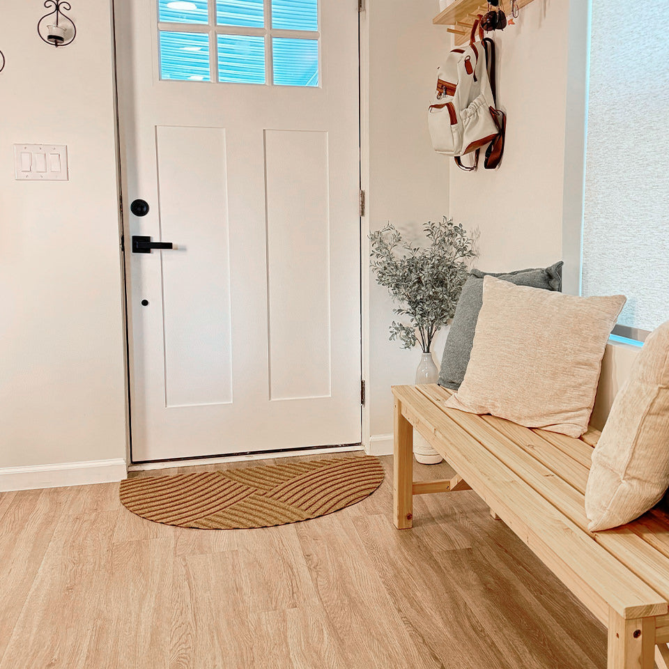 A WaterHog Luxe Heartland half-round all-weather doormat at the front door of a home in the color wheat