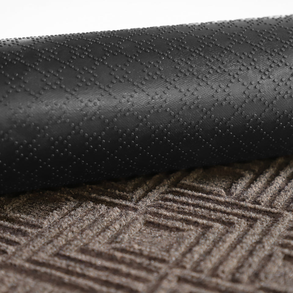 A close-up image of the all-weather Labyrinth mat half rolled showing both the rubber backing and greige surface.