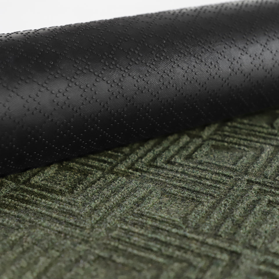 A close-up image of the all-weather Labyrinth mat half rolled showing both the rubber backing and olive surface.