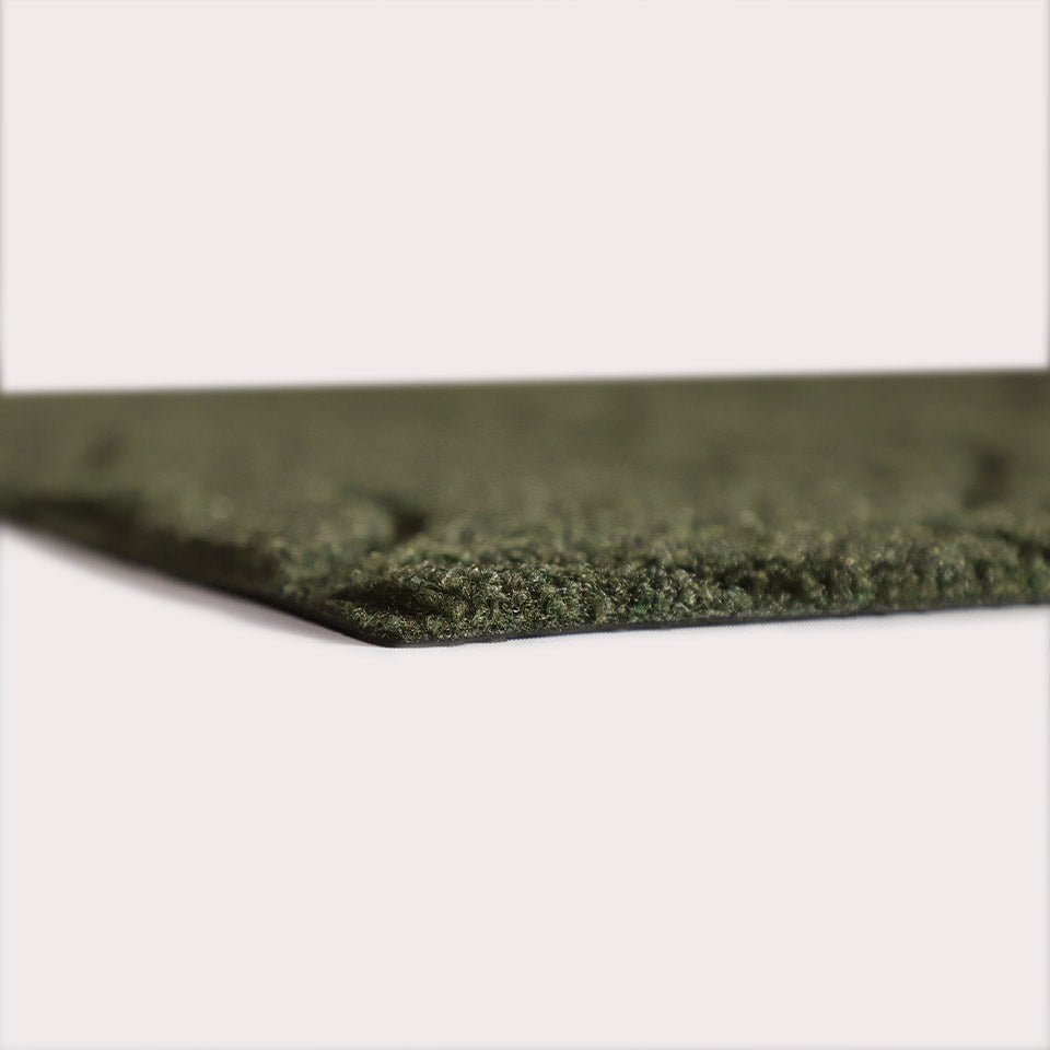 Profile corner image of the Magnolia doormat in olive, showing the overall 3/8” height and rubber backing. 