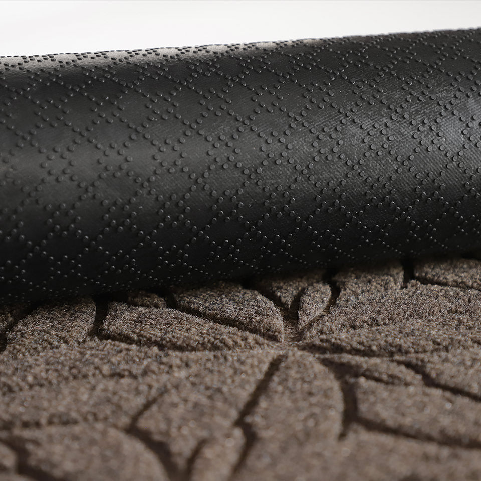 A close-up image of the all-weather Magnolia mat half rolled showing both the rubber backing and greige surface.