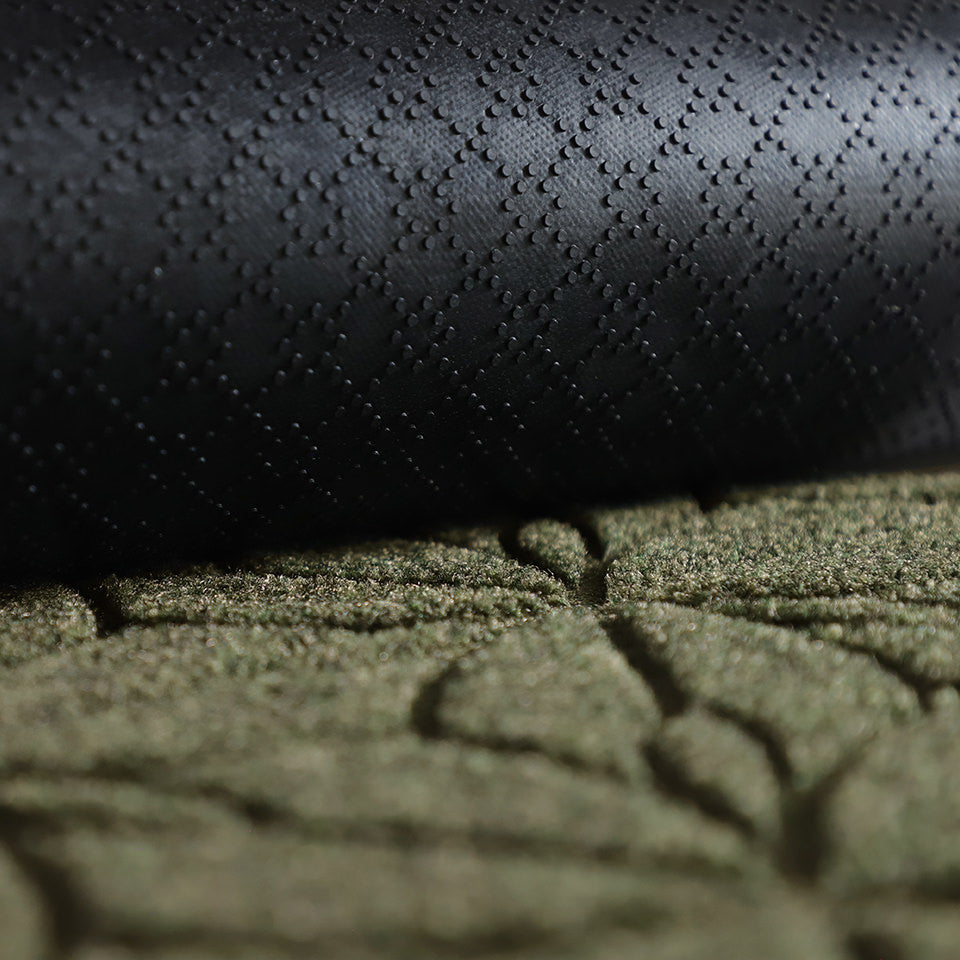A close-up image of the all-weather Magnolia mat half rolled showing both the rubber backing and olive surface.