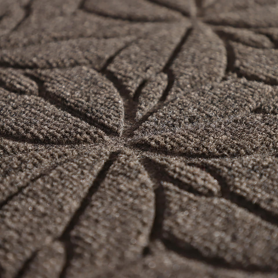 Up close, detailed image of Magnolia’s surface, capturing the floral design carved out by the bi-level surface, shown in greige.