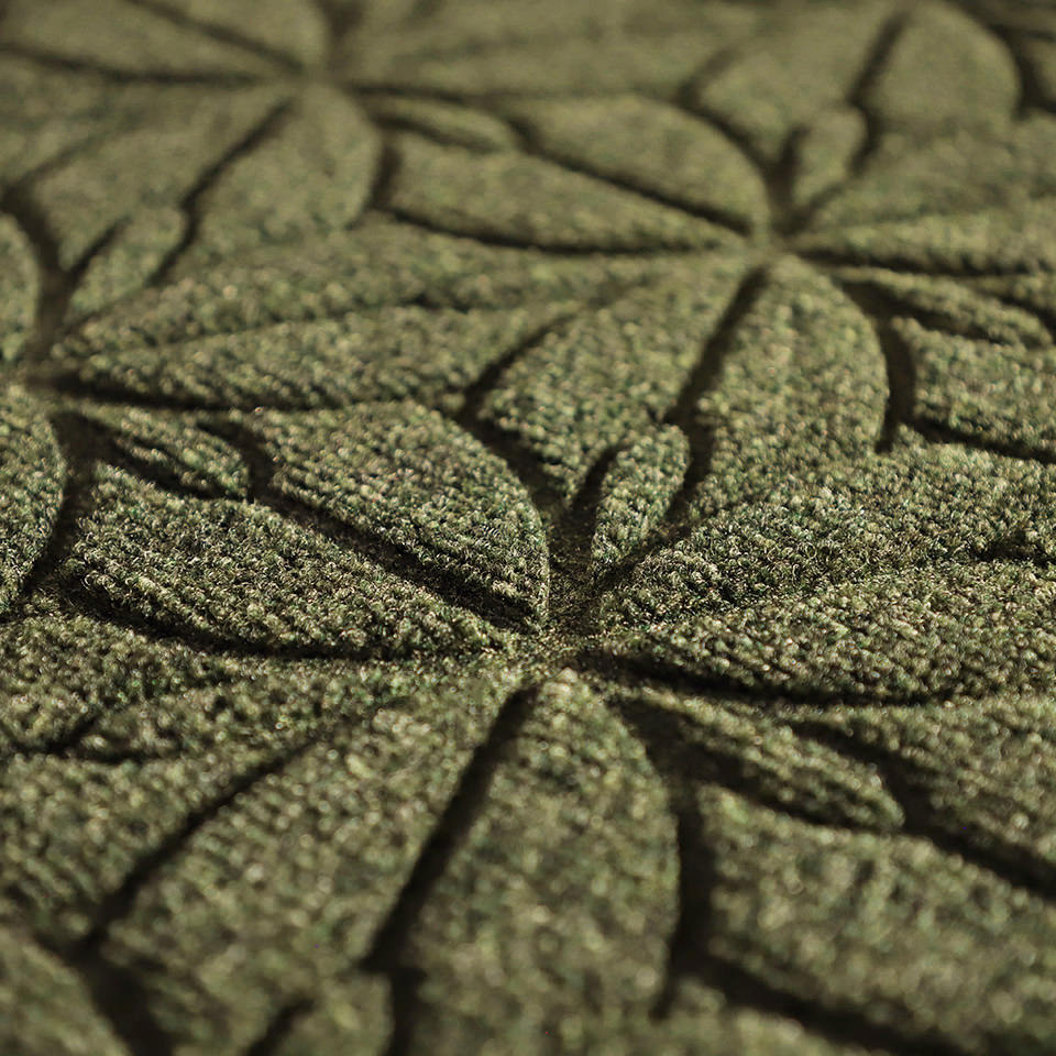 Up close, detailed image of Magnolia’s surface, capturing the floral design carved out by the bi-level surface, shown in  the earthy olive green.
