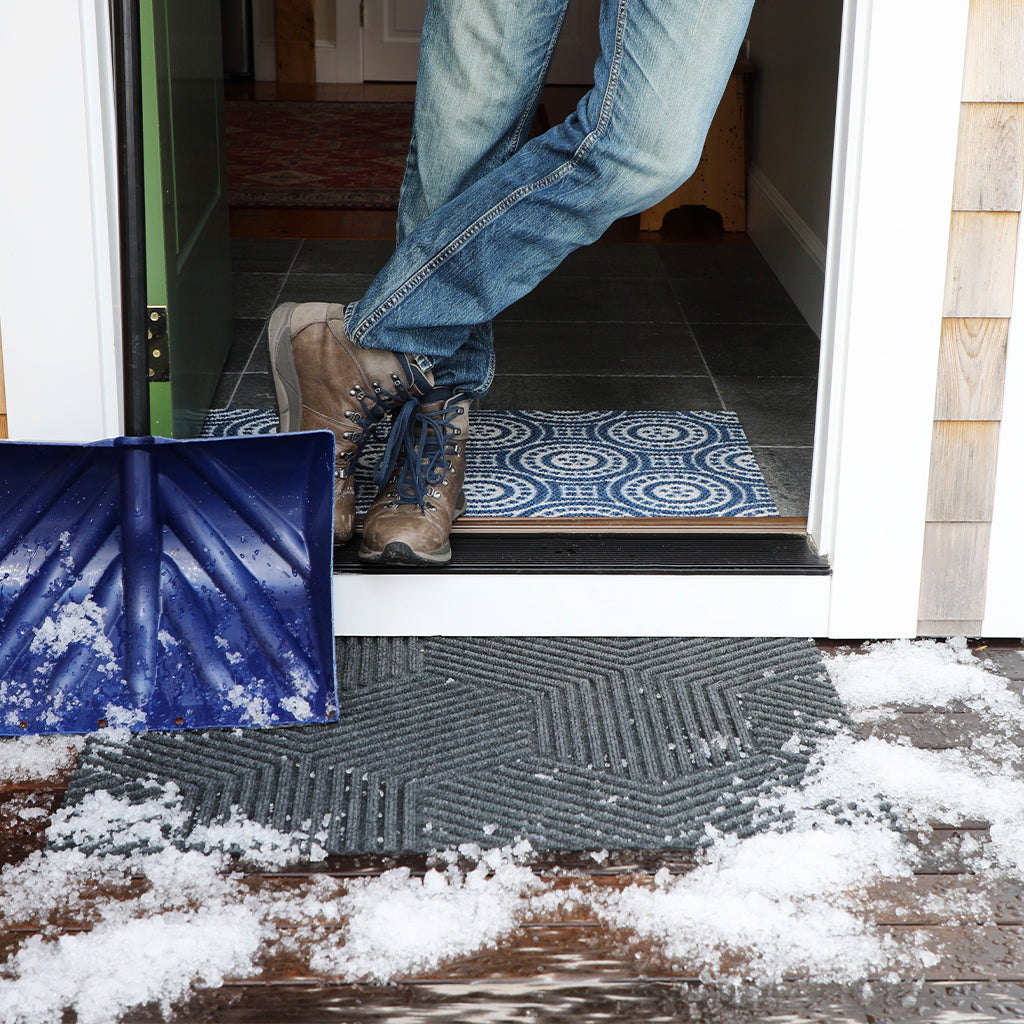 Durable and long lasting all-weather doormat placed at front door with winter snow. These long lasting doormats are great at scraping snow, ice, dirt, rain, and mud from the bottom of shoes and boots.